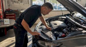 Man inspecting car engine in driveway
