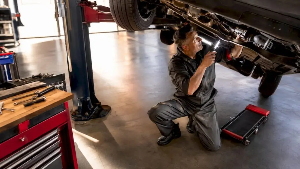 Mechanic inspecting car drivetrain underside
