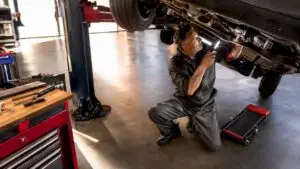 Mechanic inspecting car drivetrain underside