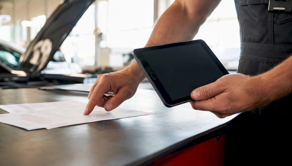 Mechanic pointing at repair-related documents in garage