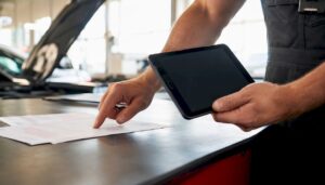 Mechanic pointing at repair-related documents in garage