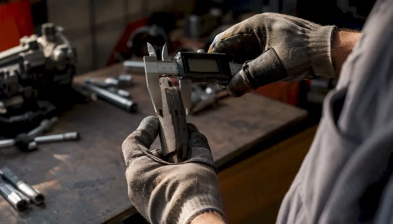 Mechanic measuring brake pad thickness