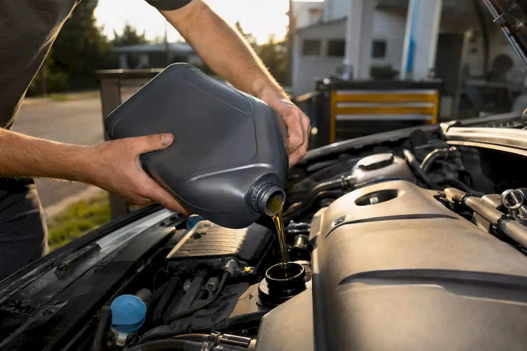 Hands pouring oil into engine filler neck