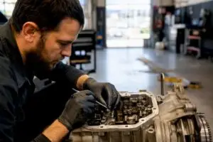 Technician inspecting repaired car part closely