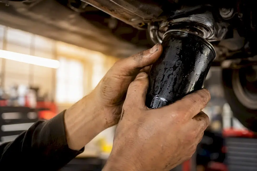 Hands removing car oil filter in shop bay