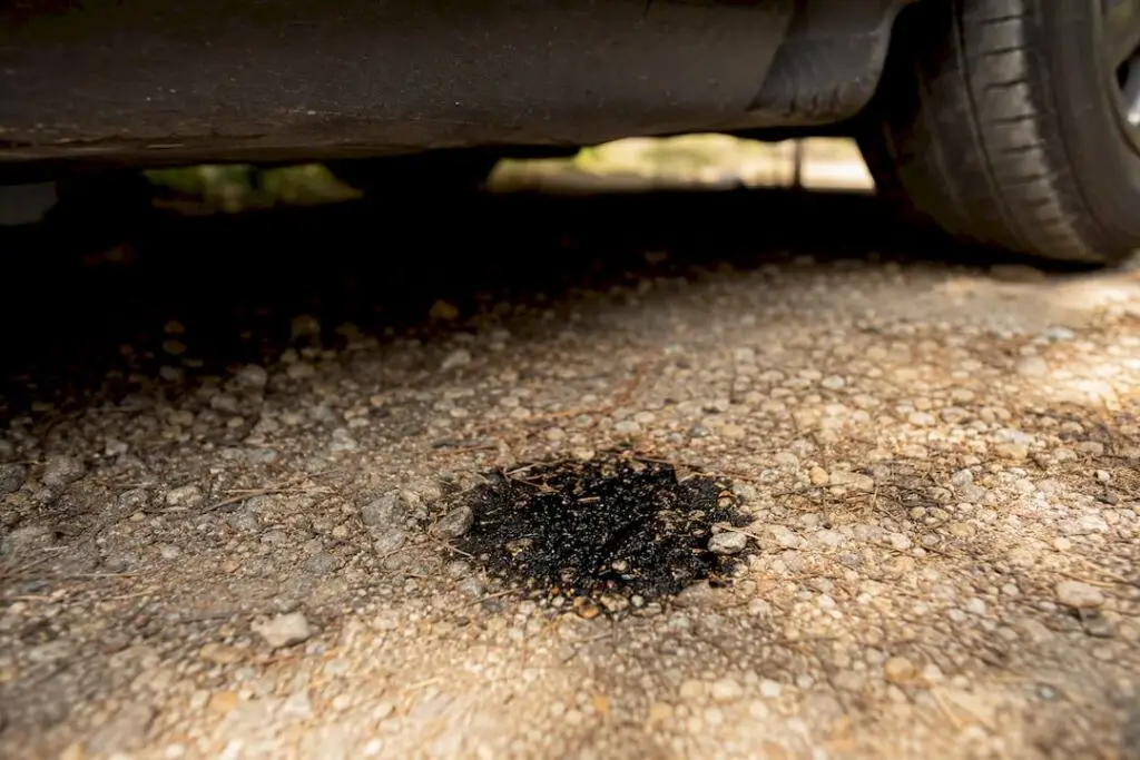 Oil drip spot on concrete driveway under car