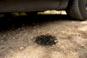 Oil drip spot on concrete driveway under car