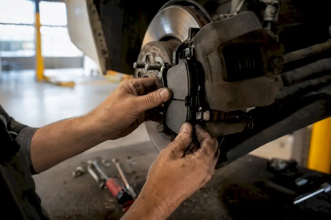Hands replacing brake pads in brake assembly