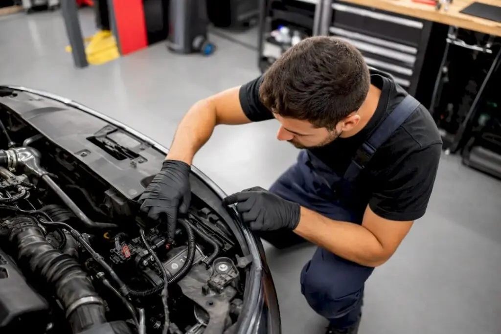 Technician inspecting engine bay readiness monitor sensor