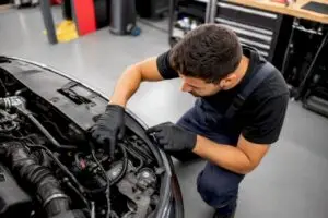 Technician inspecting engine bay readiness monitor sensor