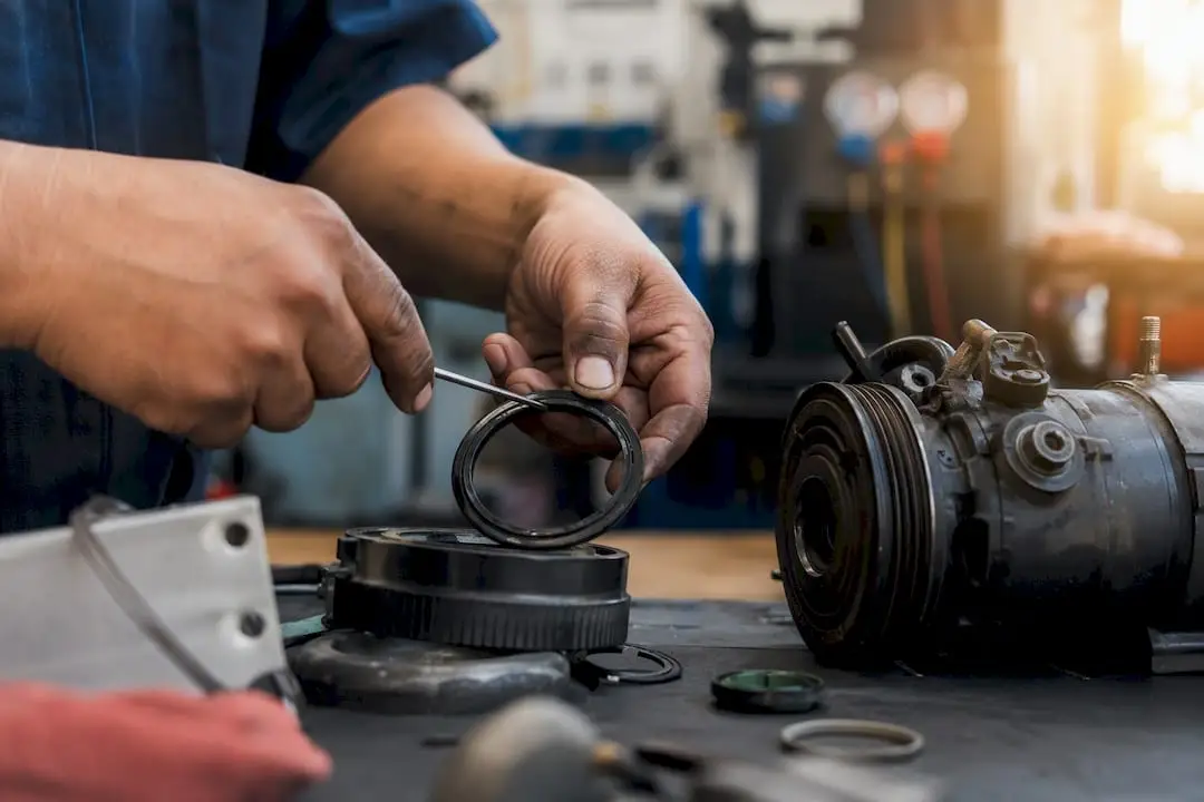Hands repairing AC compressor clutch and seal close-up