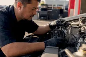 Technician inspecting car AC compressor close-up