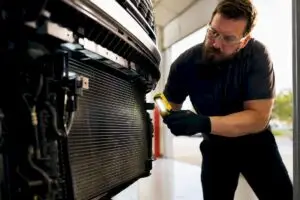 Technician inspecting car AC condenser