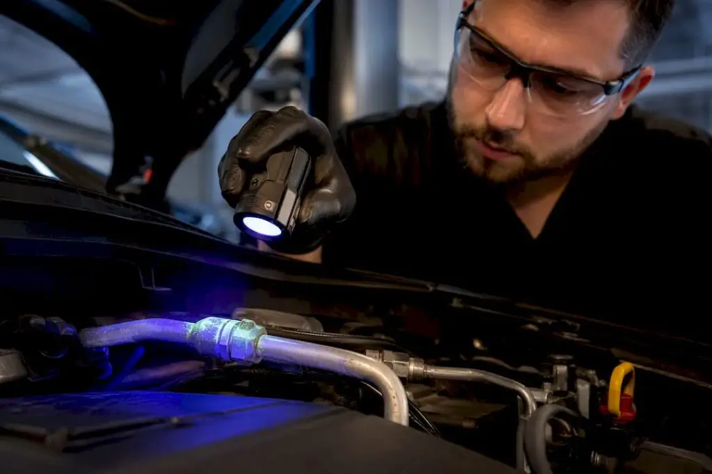 Technician tracing fluorescent A/C leak dye