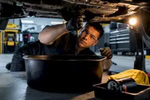 Technician draining oil in service bay