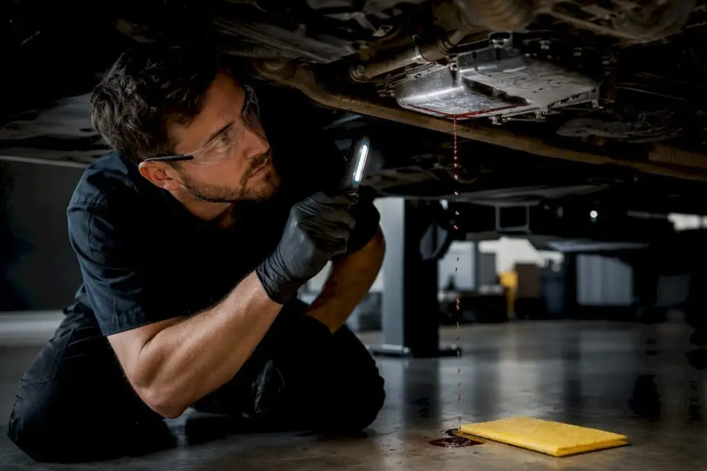 Technician inspecting transmission fluid leak