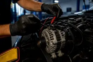 Technician testing alternator output in service bay