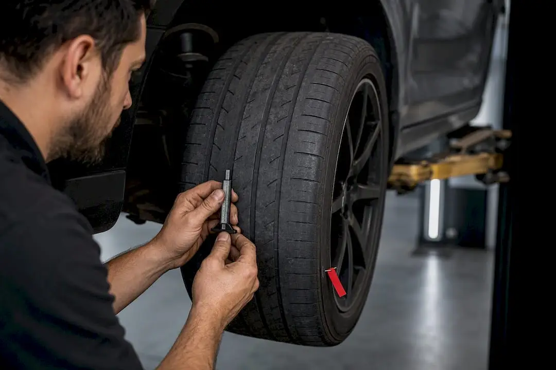 Technician checking worn tire before replacement