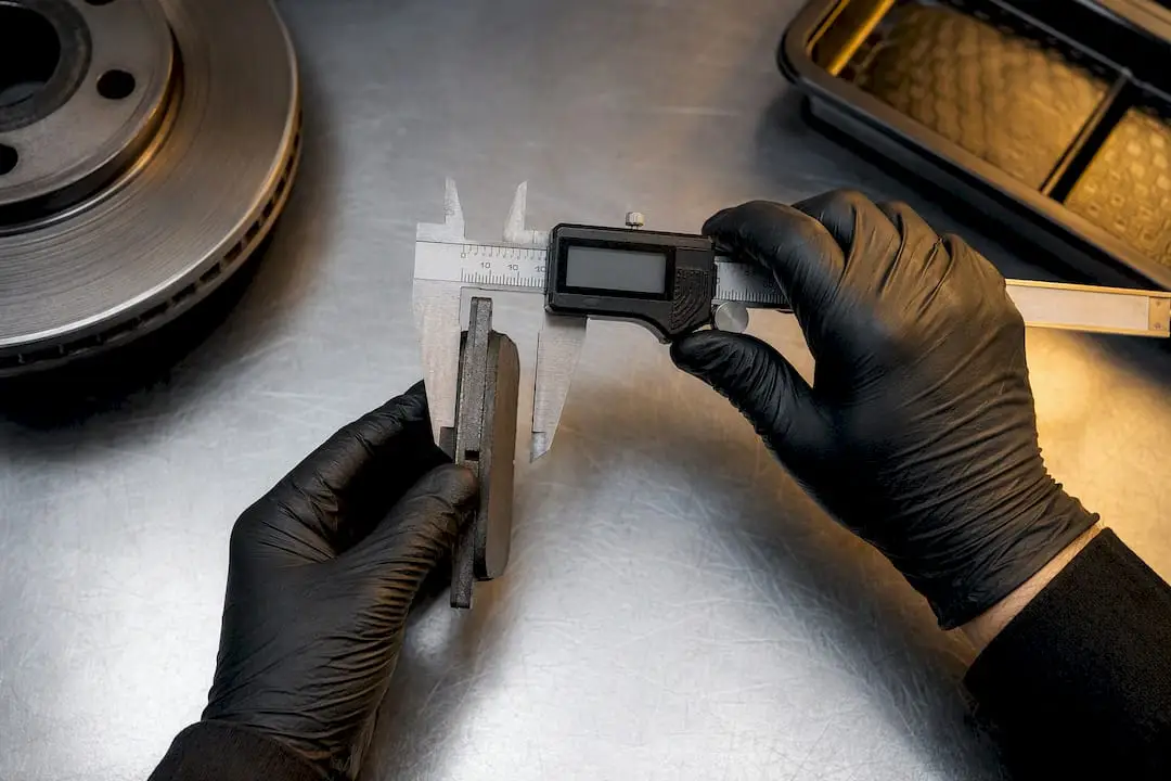 Technician measuring brake pad thickness