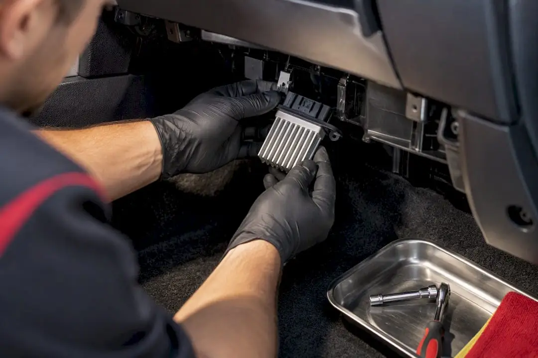 Technician removing blower resistor behind glove box