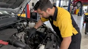 Technician inspecting serpentine belt in engine bay