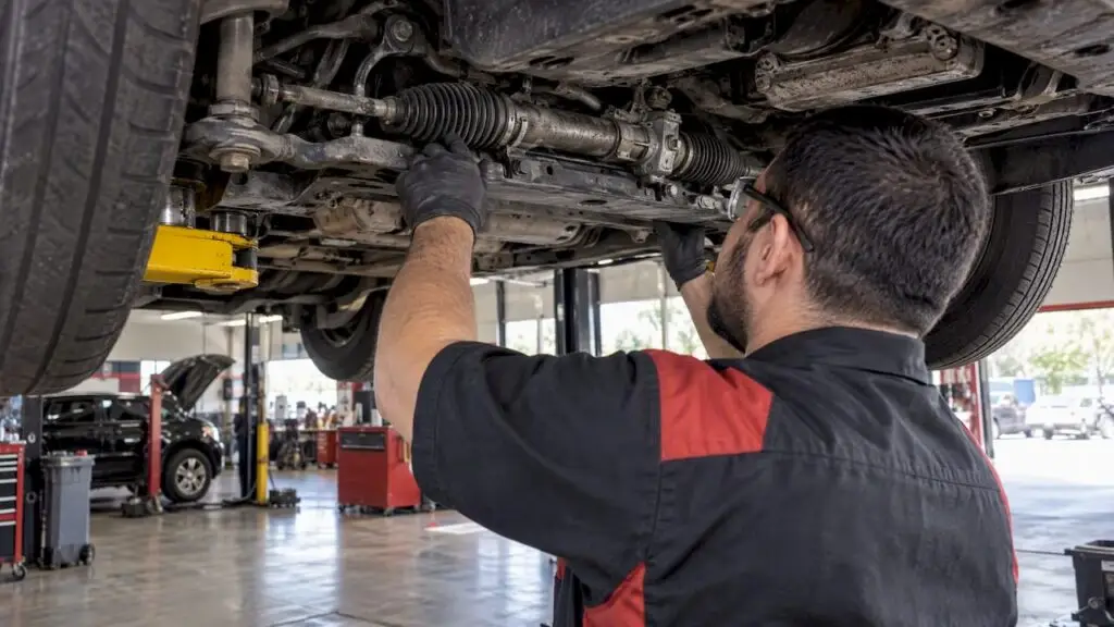 Technician inspecting vehicle steering rack