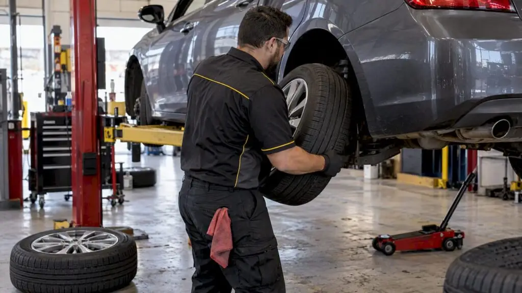 Technician rotating tires in service bay