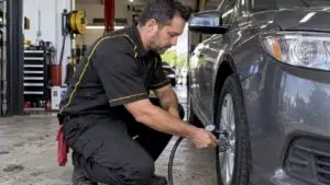 Technician checks a sedan tire with gauge