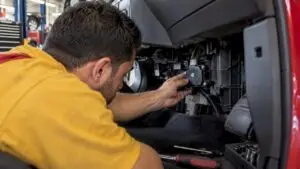 Technician inspecting an actuator beneath dashboard