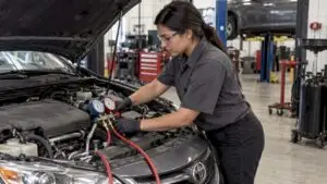 Technician checking car A/C manifold gauges